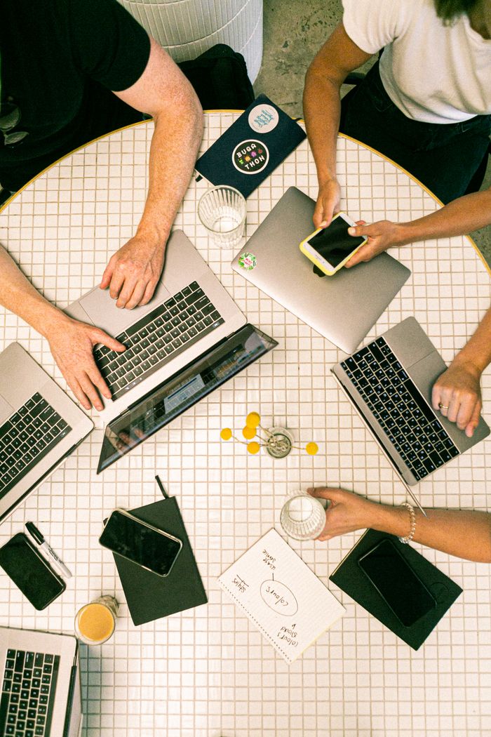 Vue de dessus d’une équipe collaborant avec des ordinateurs portables, des téléphones et des notes dans un bureau moderne.